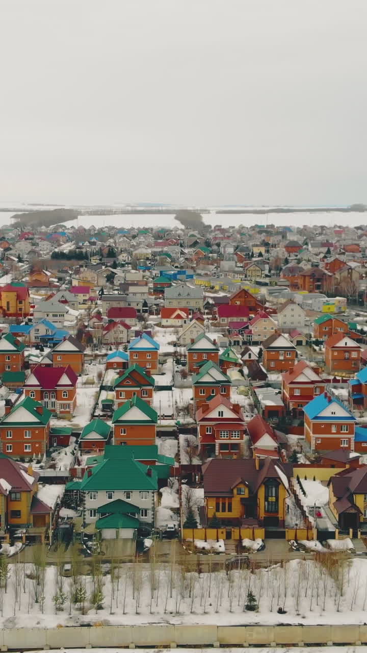 giant cottage complex with multicolored houses against snowy wasteland on nasty early spring day aerial view