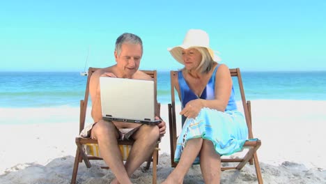 un anciano mostrando a su esposa un video en la computadora portátil
