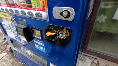 person inserting coin into vending machine slot