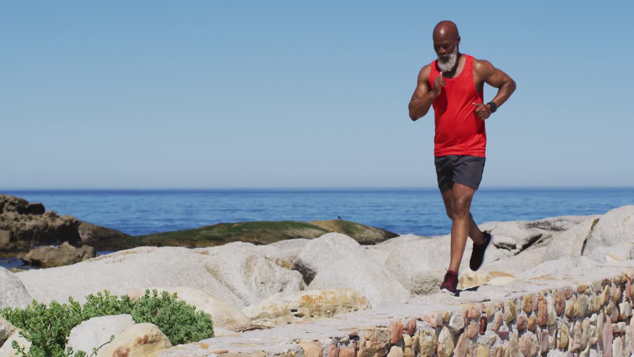 Senior african american man exercising running on rocks by the sea