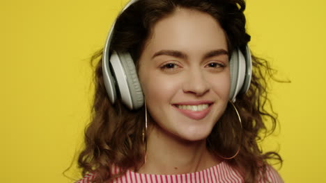 Young-woman-listen-music-in-headphones.-Happy-girl-in-headphone-on-yellow