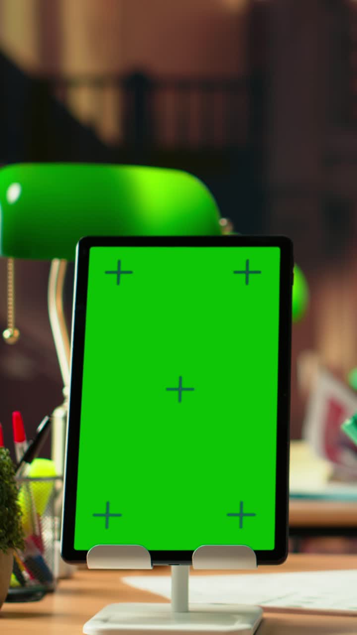 Lodret tablet med grøn skærmvisning på et kontorbord.
