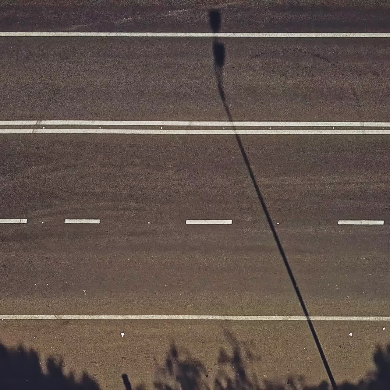 Pedestrian crossing with red and white stripes on the road and cars going by outdoors. Vertical stripes on the road to show drivers the approach of zebra crossing. Camera motion left