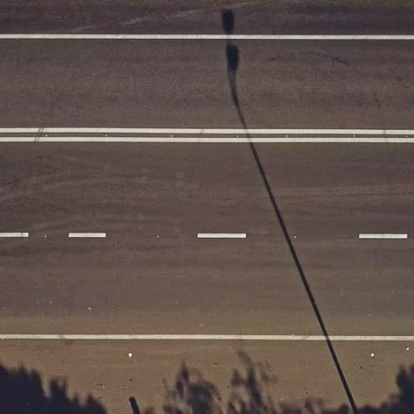 pedestrian crossing with red and white stripes on the road and cars going by outdoors. vertical stripes on the road to show drivers the approach of zebra crossing. camera motion left