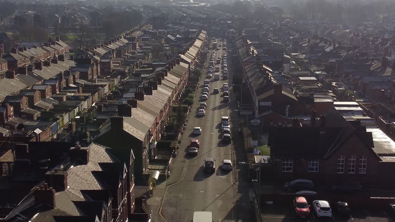 일출 시 시내 중심가로 이어지는 긴 도로가 있는 빅토리아 시대의 계단식 주택이 줄지어 있는 공중 상승 전망