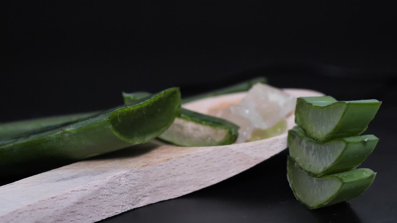 검정색 배경에 얇게 썬 신선한 알로에 베라, 화장품 및 스킨케어 제품 프레젠테이션을 위한 녹색 허브 개념, 둥근 부드러운 동작