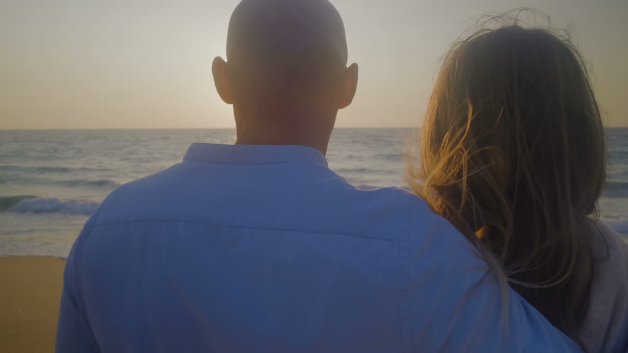 바다 위 에 해 가 지는 것 을 바라보며 포옹 하는 부부