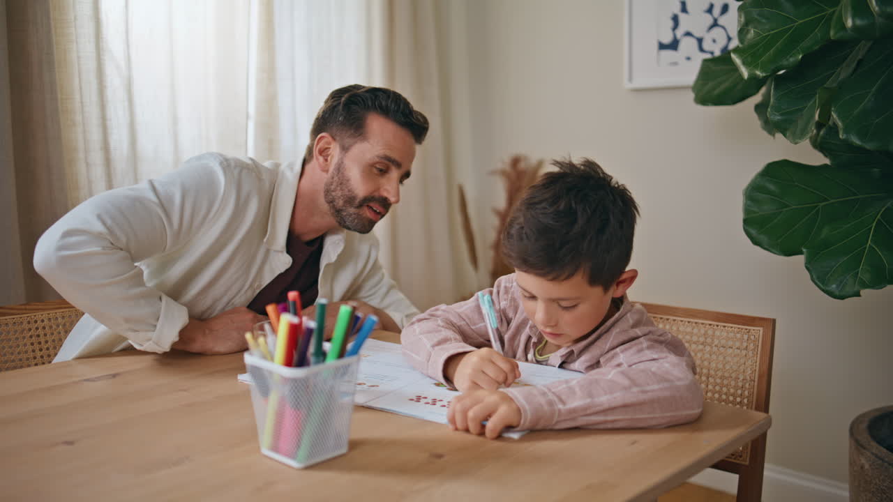 Father helping son studying at home closeup. Little schoolboy doing homework