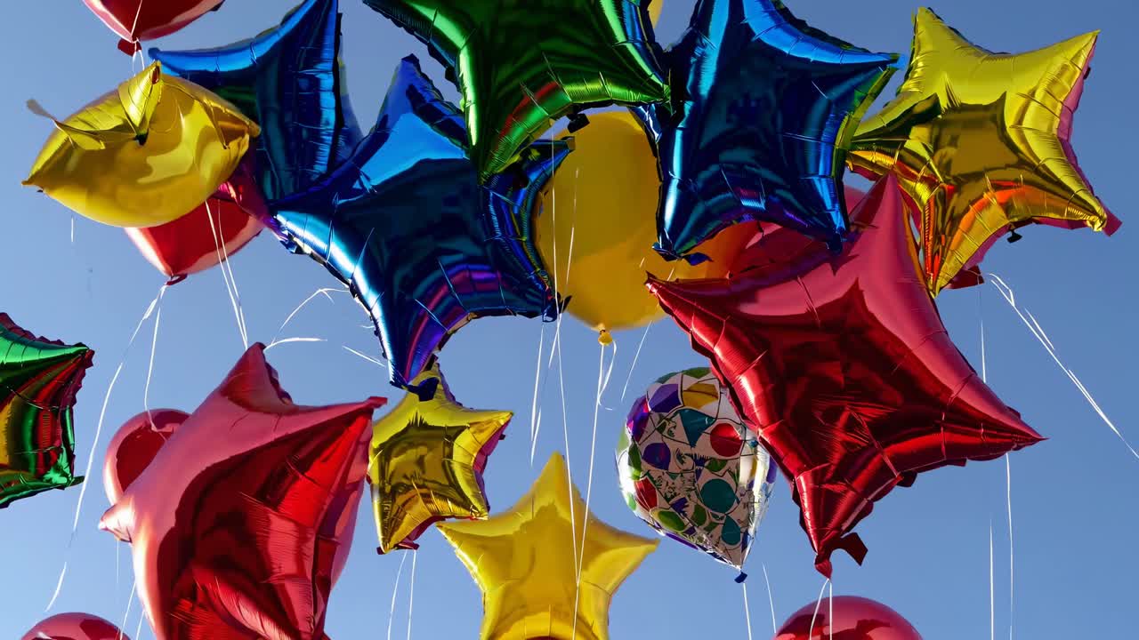Vibrant star-shaped balloons in red, blue, green, and yellow float against a clear sky