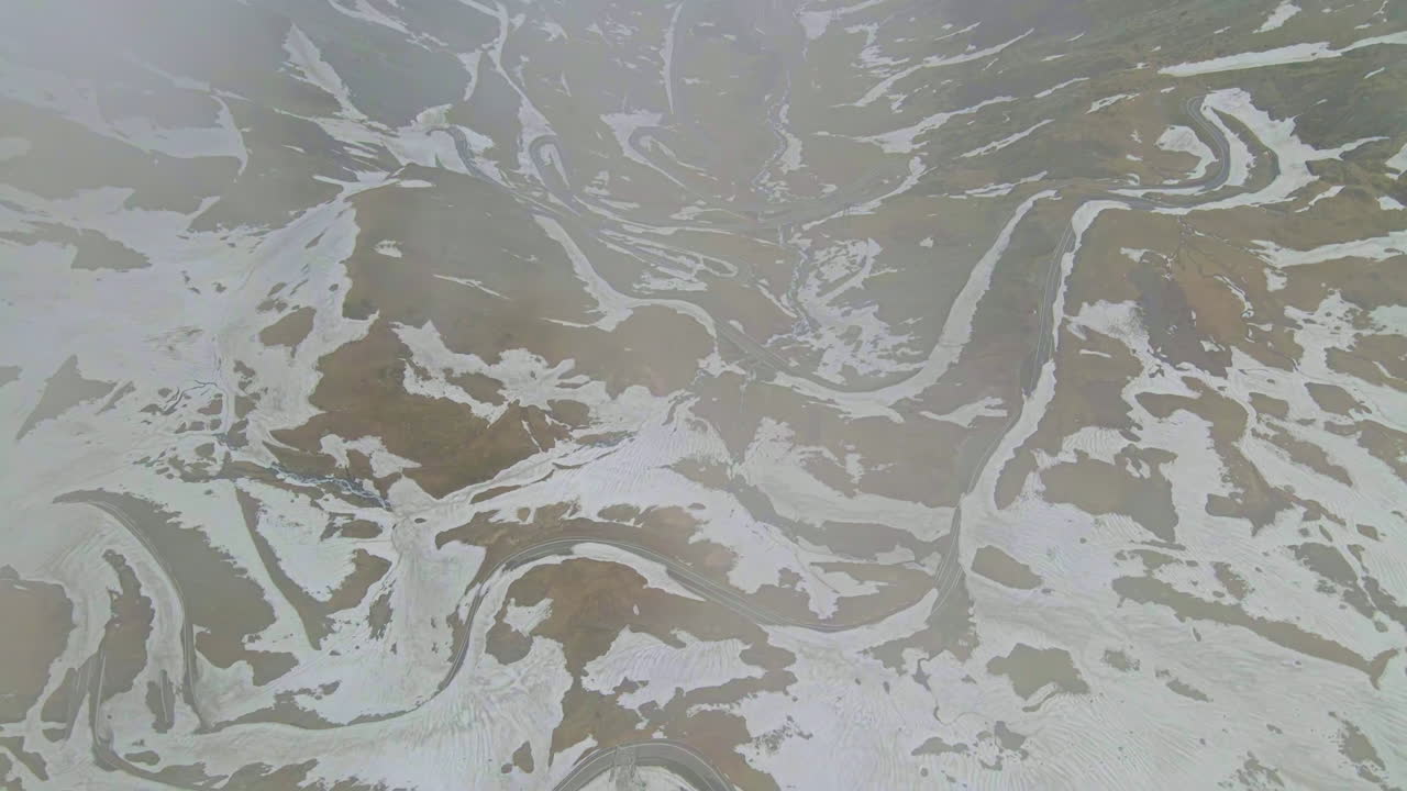 Vista aerea con drone della natura in Romania. Strada Transfăgărășan con auto tra i monti Carpazi, pendii montuosi innevati in una valle