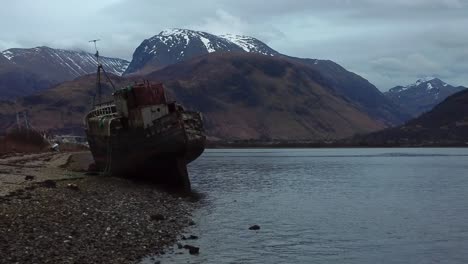 Aerial-drone-video-in-4K-of-The-Old-Boat-of-Corpach-in-Fort-William-with-a-snow-topped-Nevis-in-the-background