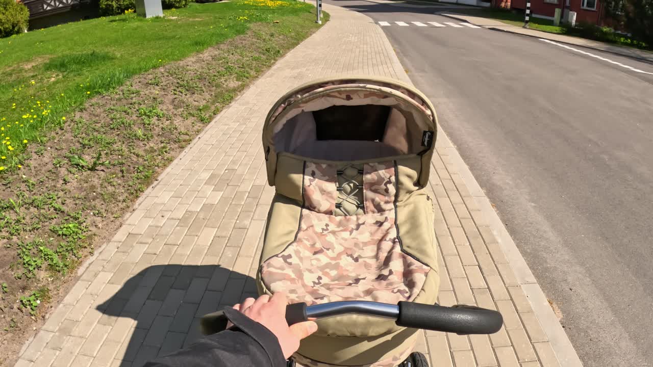 Father pushing a stroller on a sidewalk in urban environment.