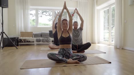 Concentrated-young-people-practicing-yoga-indoors