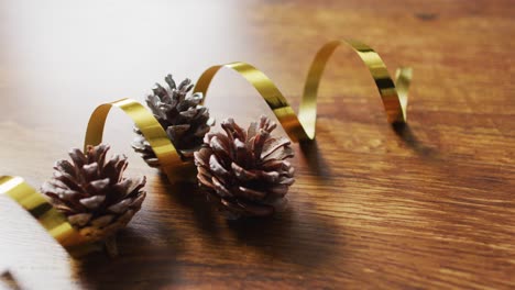 Video-of-christmas-decorations-with-pine-cones-and-copy-space-on-wooden-background