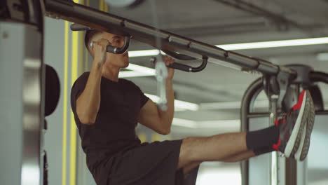 strong man doing l-sit pull ups in gym