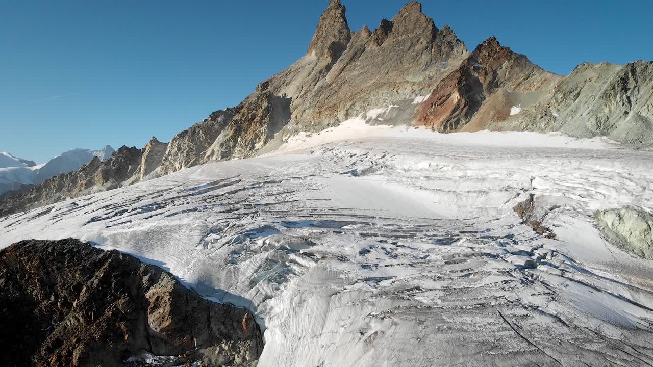 sobrevuelo aéreo sobre un glaciar cerca de arolla en valais, suiza con los picos de aiguilles rouges iluminados por el sol de la mañana temprano