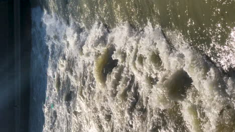 VERTICAL-view-of-powerful-river-water-crashing-down-a-weir-waterfall