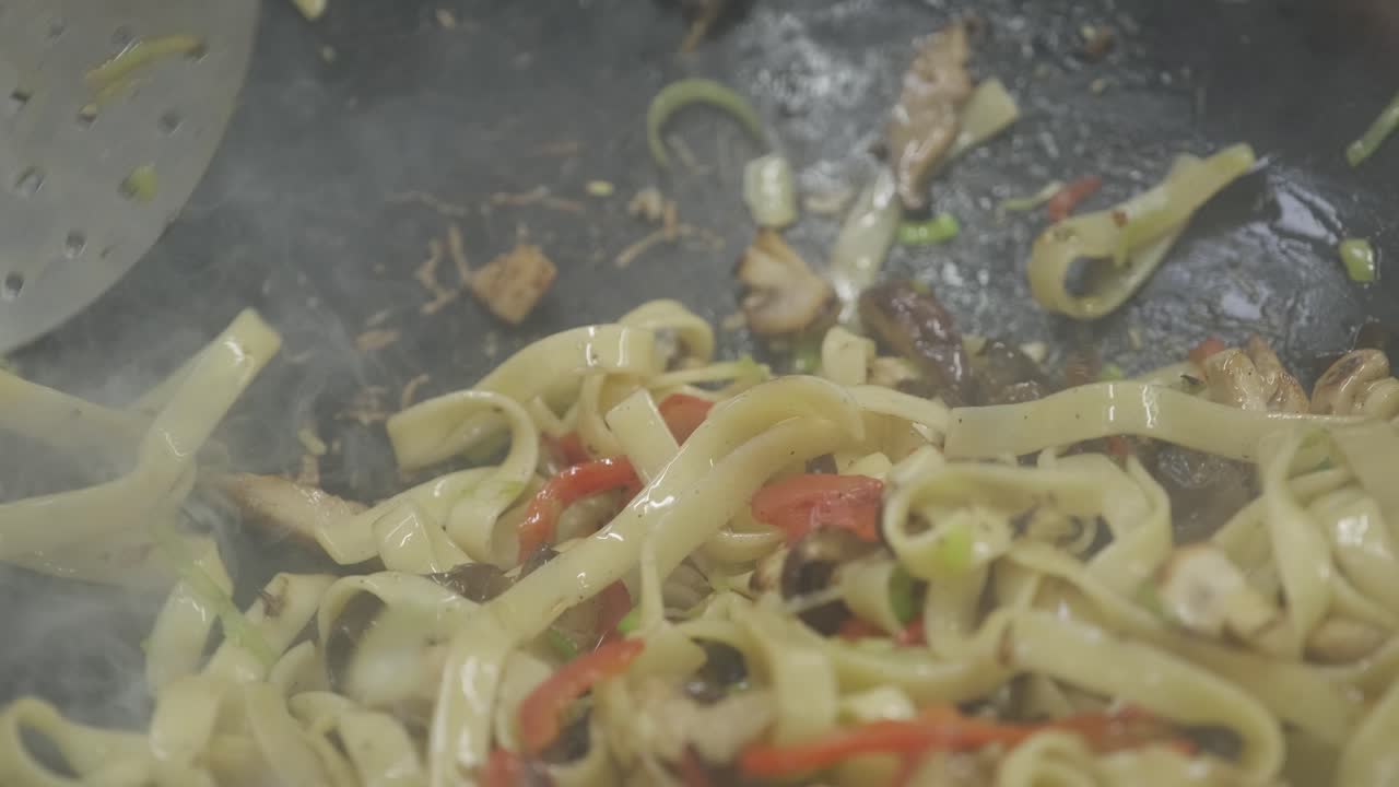 un plato de fideos y carne se cocina en una sartén
