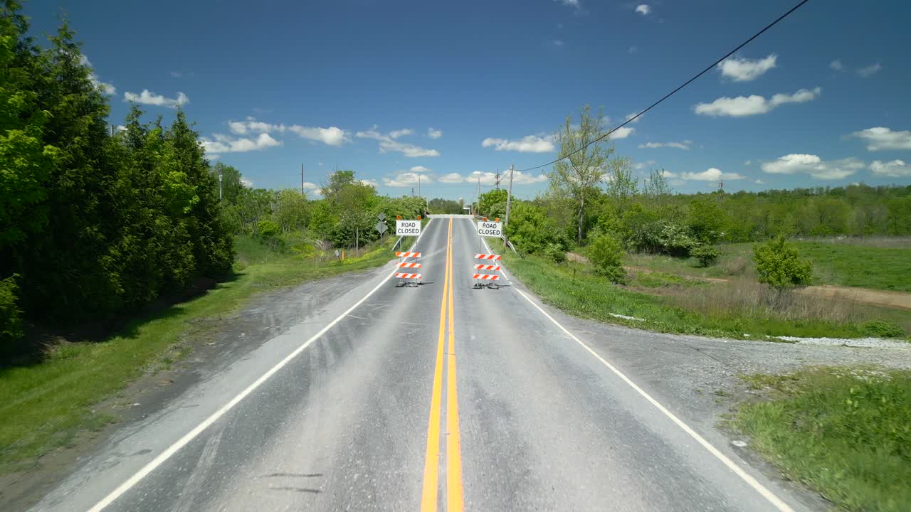 Aerial drone view of a road closed sign in the road. Daytime with bright blue sky.