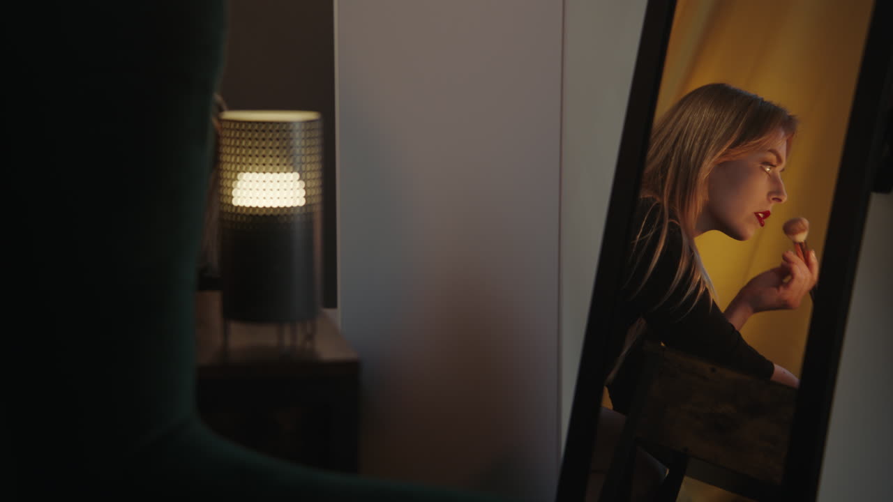Woman Applying Makeup in Front of a Mirror at Night