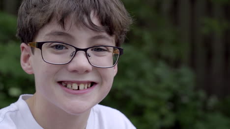 Cute boy with glasses outside smiles at camera
