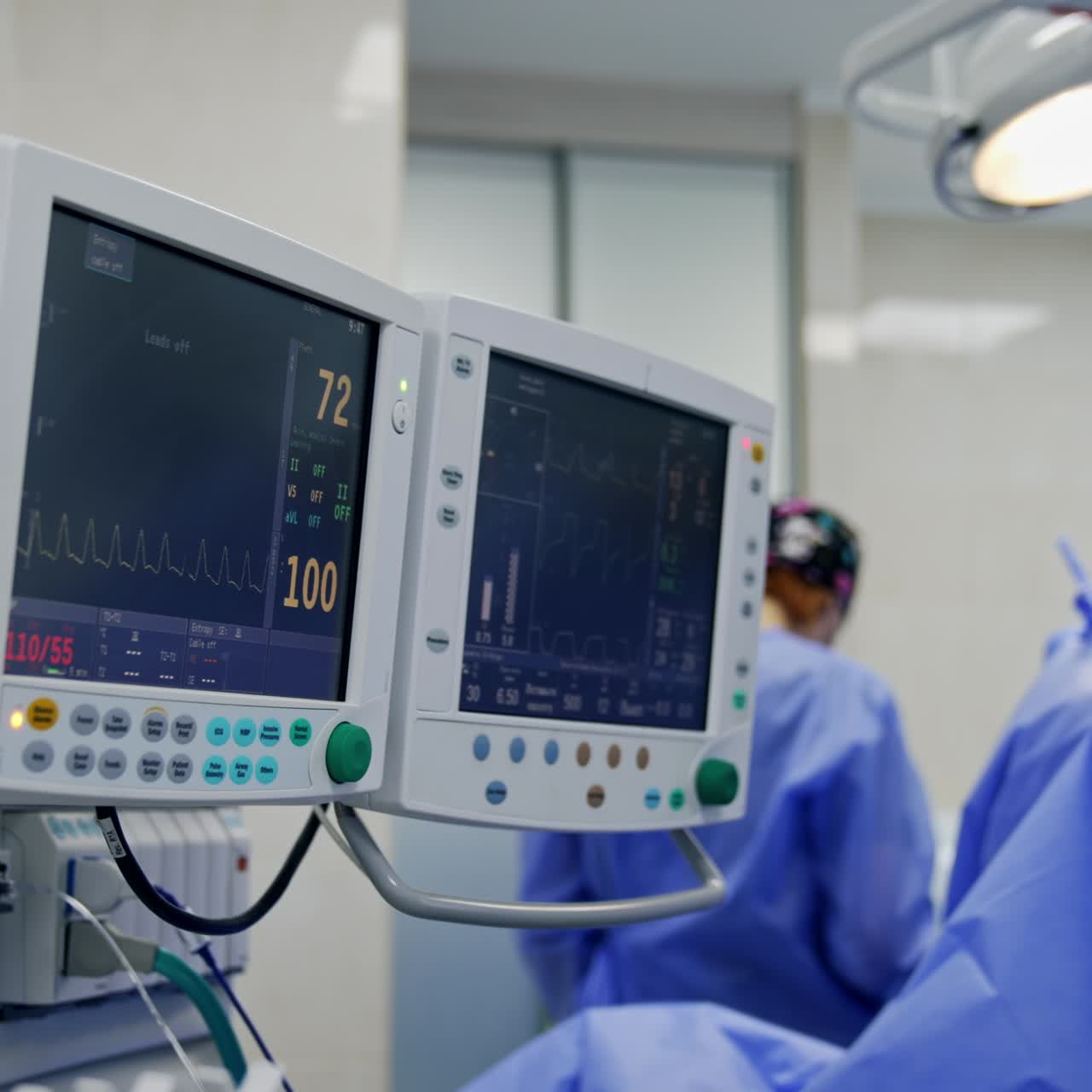 Monitors displaying the life parameters of the patient at surgical procedure. Doctor's team working at backdrop