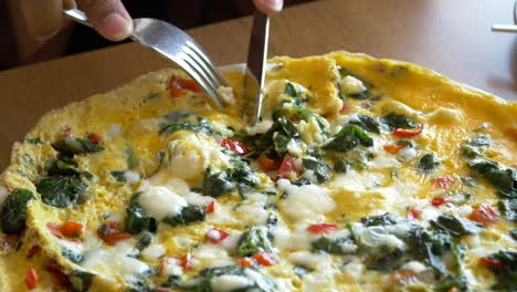 person eating a delicious spinach and cheese omelette