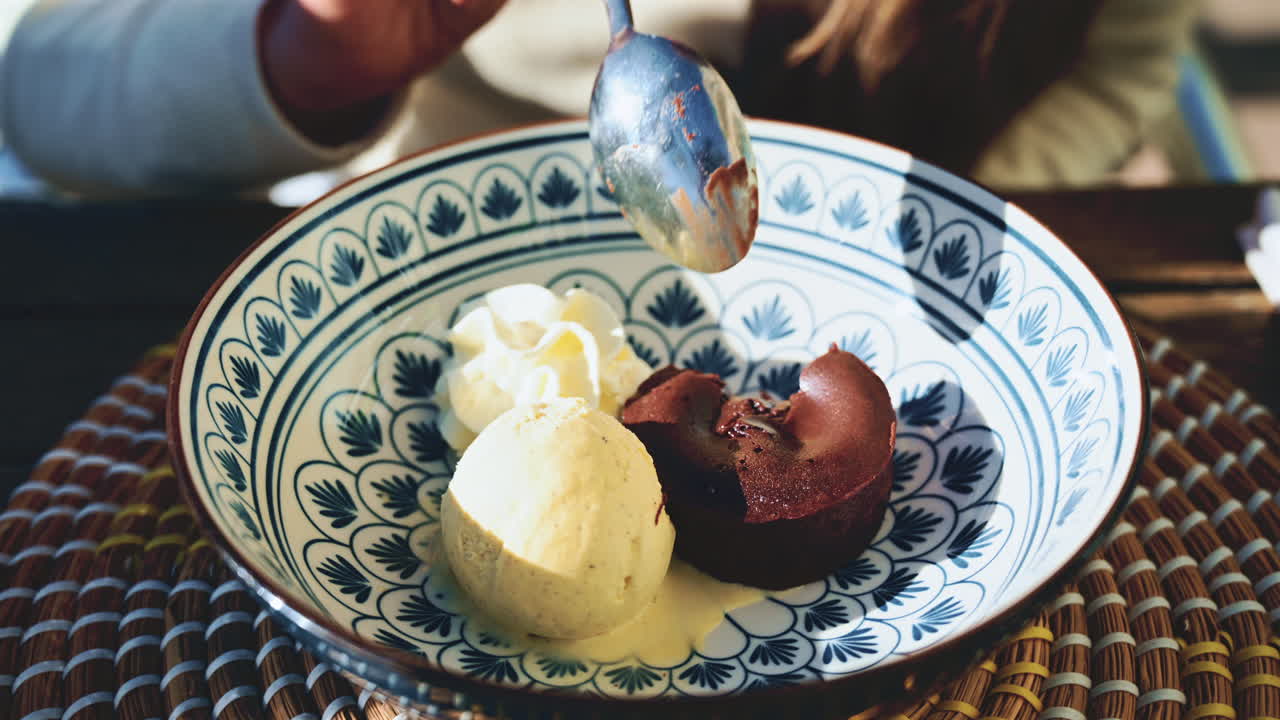 Woman spinning a plate with warm chocolate fondant served with vanilla ice cream and whipped cream