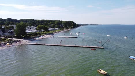 Aerial-Camp-Site-Baltic-Sea-with-a-pier-reaching-into-the-ocean-and-people-enjoying-there-vacation