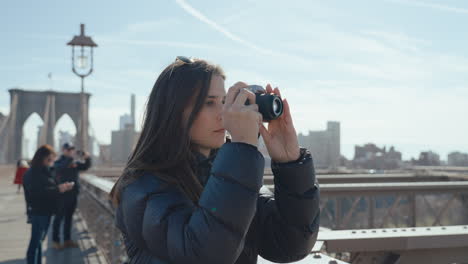 woman taking photo of brooklyn bridge
