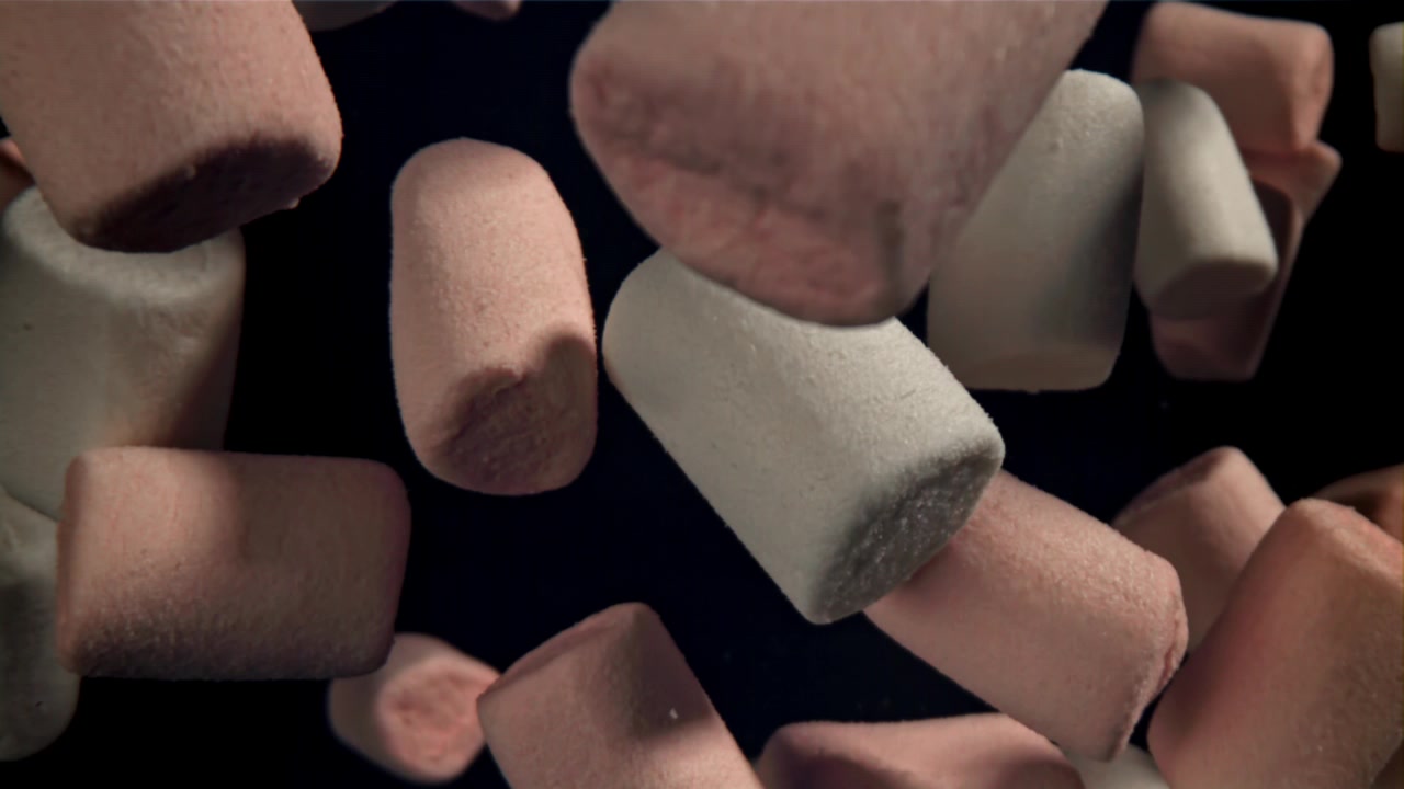 Marshmallow dolci rosa e bianchi che cadono al rallentatore.