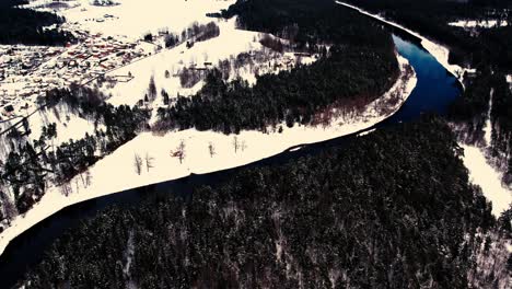 a winding river near a small town with a forest massif