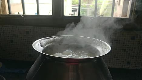 pot cooking rice in a traditional way by boiling water in a black background with white smoke coming in slow motion