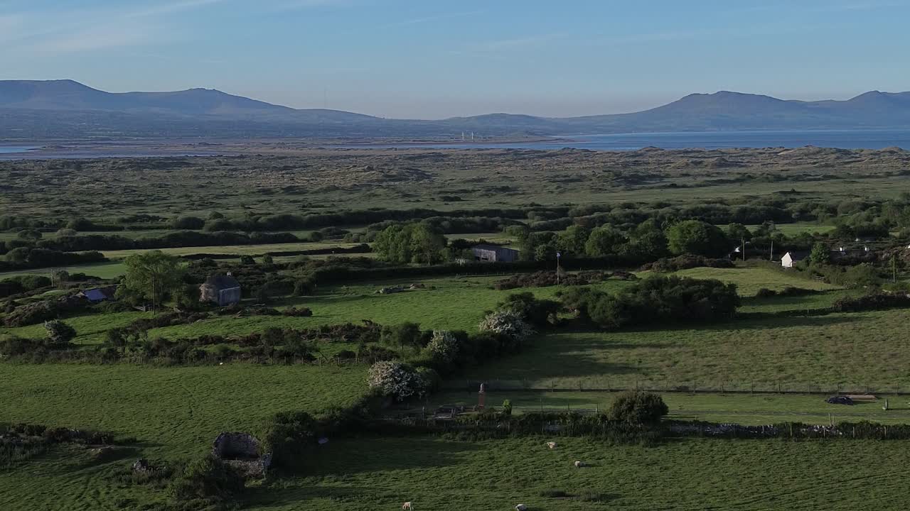 Aerial view looking across idyllic Welsh meadow under Snowdonia mountains in the distance