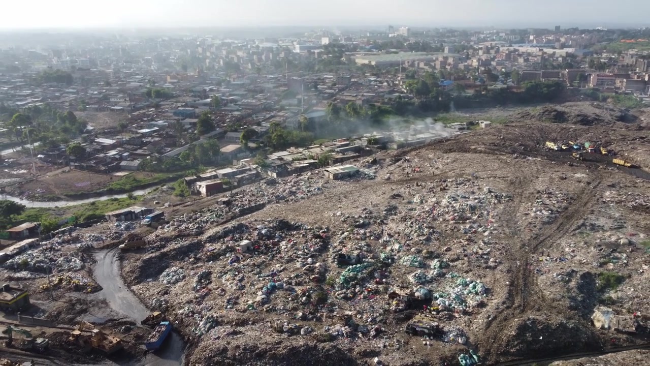 Drone shot of the Dandora landfill with workers and trucks in Nairobi, Kenya.