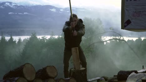 Long-haired-guy-chopping-wood-and-splitting-the-tree-trunk-into-peaches