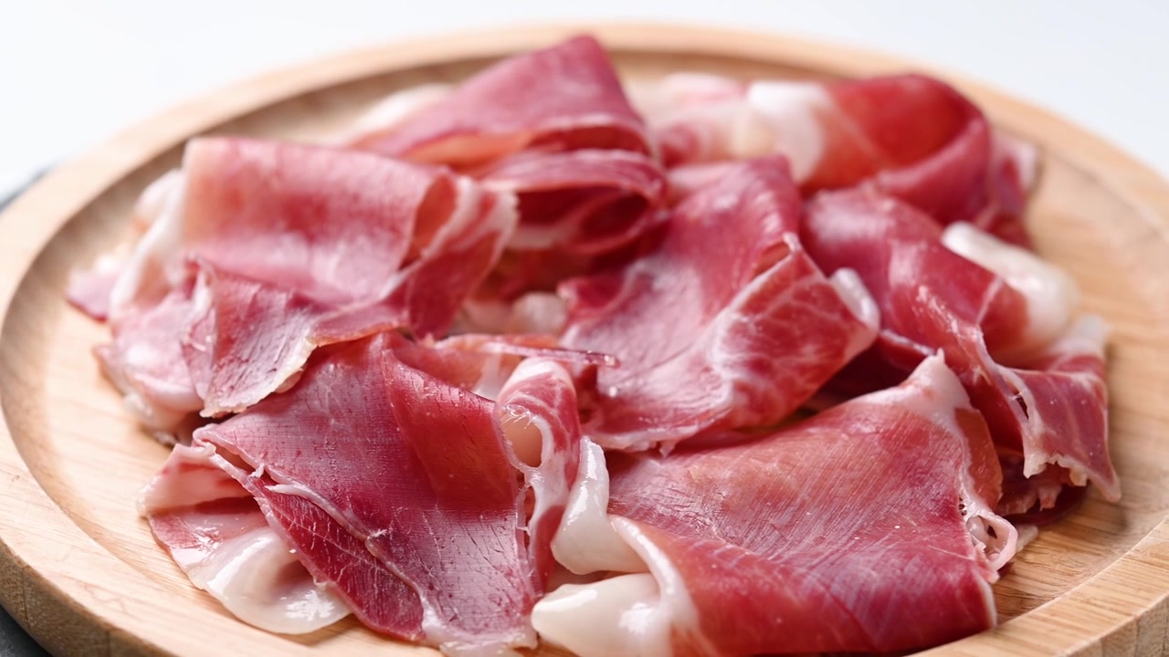 Prosciutto affettato sottile su un tagliere di legno