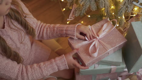 little girl unties the bow of a christmas present