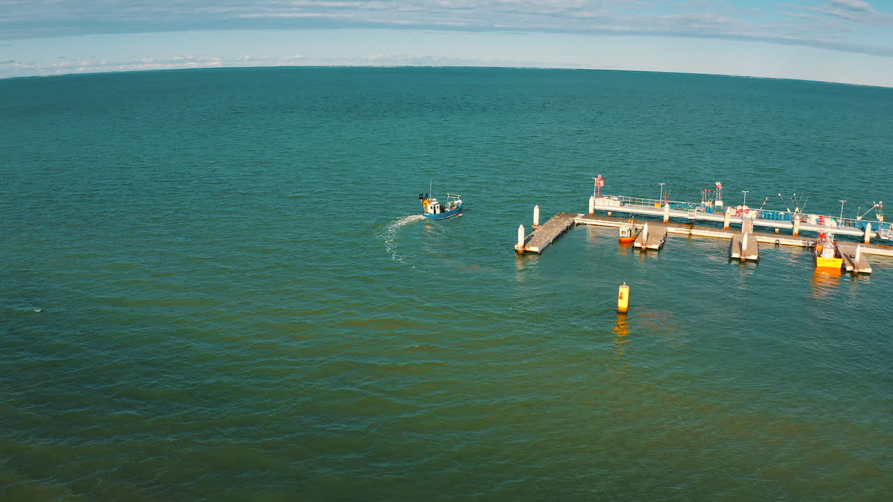 Aerial view of fishing boat going near the pier on the baltic sea