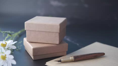 gift boxes, pen, and flowers on a dark desk