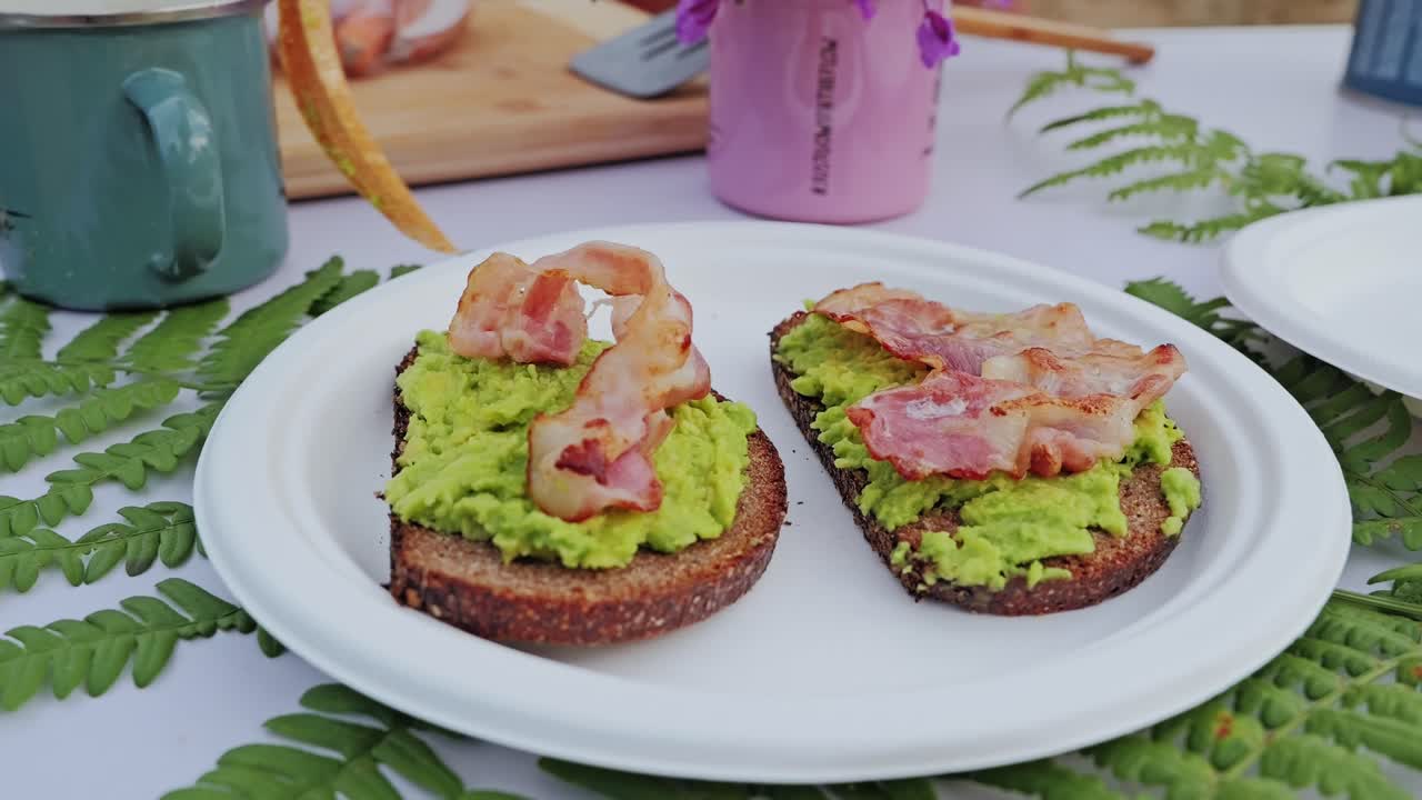 Slow camera motion captures calm layering of crispy bacon on green toast