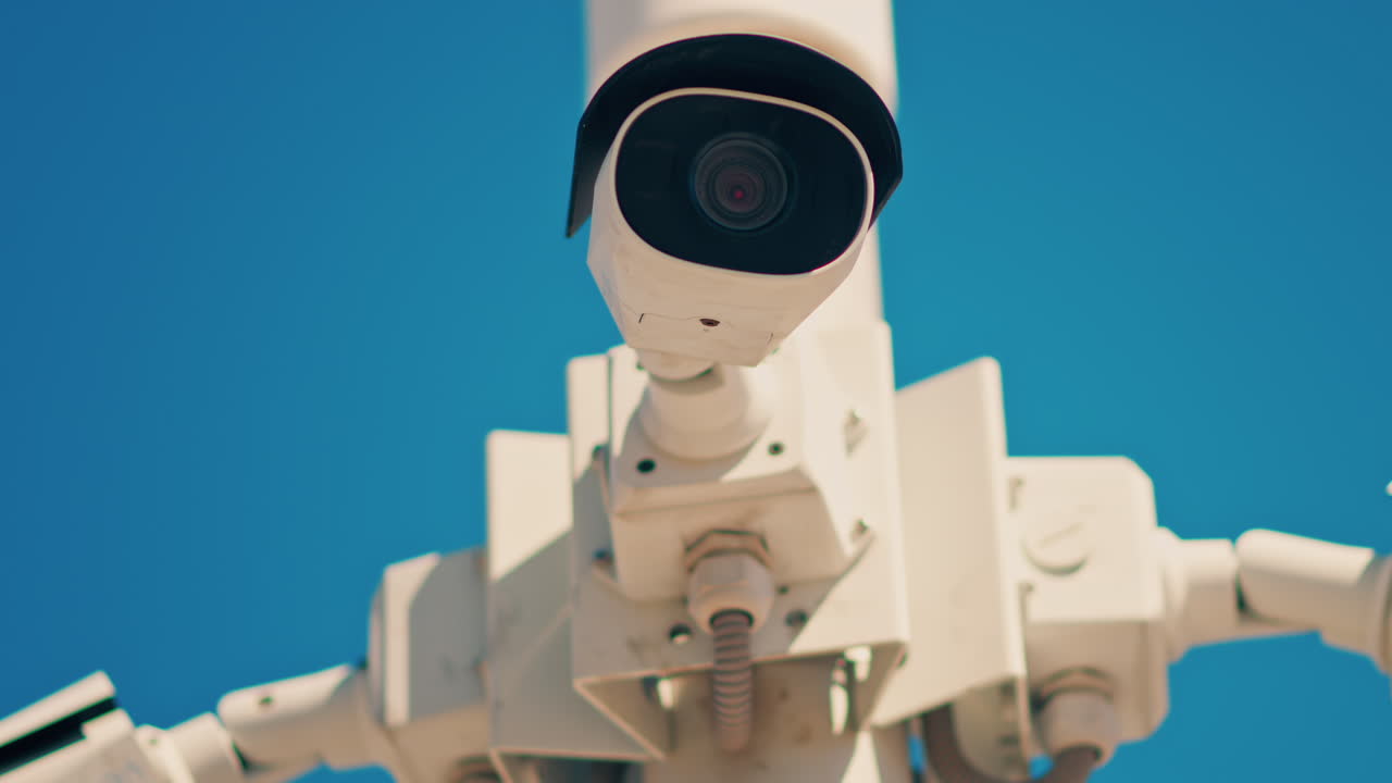 Close up of a white surveillance camera on a blue sky background