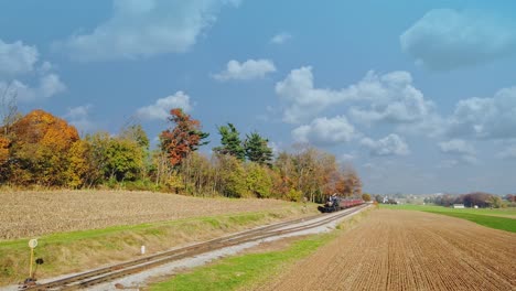 Eine-Antike,-Restaurierte-Lokomotive-Und-Personenwagen,-Die-Sich-An-Einem-Sonnigen-Tag-Nähern-Und-Durch-Die-Landschaft-Reisen,-Von-Einer-Erhöhten-Höhe-Aus-Gesehen