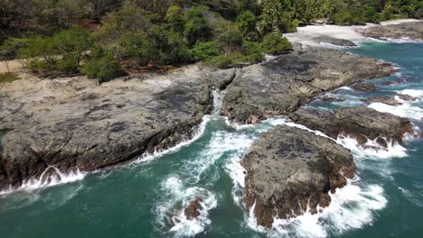 costa rica, rocky stone coast with waves splashing aginst the stones, drone shot