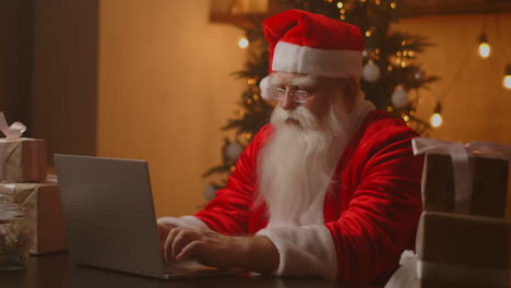 Alegre-Santa-Trabajando-En-Una-Computadora-Portátil.-Papá-Noel-Usando-El-Primer-Plano-De-La-Computadora-Portátil.-Imágenes-4k-De-Alta-Calidad