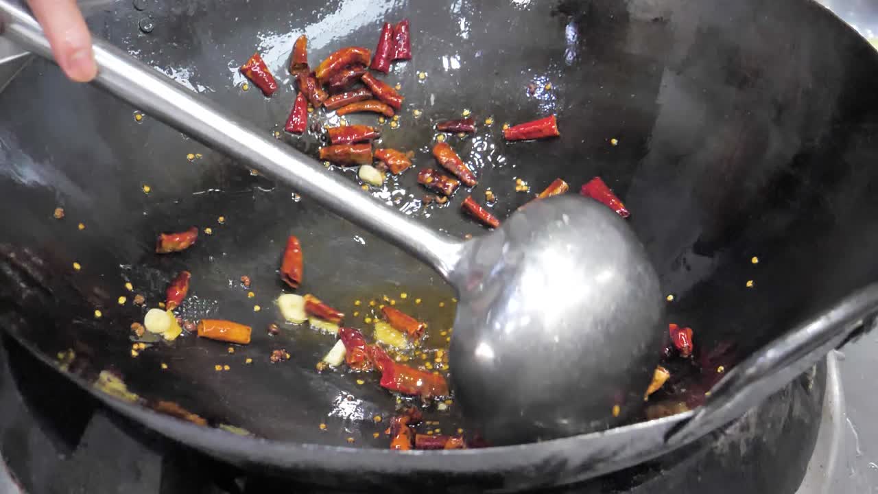 Slow-motion shot of vibrant red chilies sizzling in a hot wok, highlighting the essence of Sichuan cuisine. The oil bubbles around the spices, releasing bold flavors.