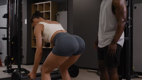 mujer levantando pesas con entrenador