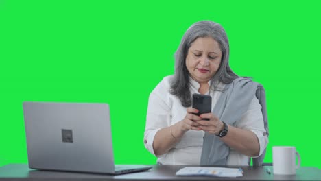 Angry-Indian-senior-female-manager-chatting-on-phone-Green-screen