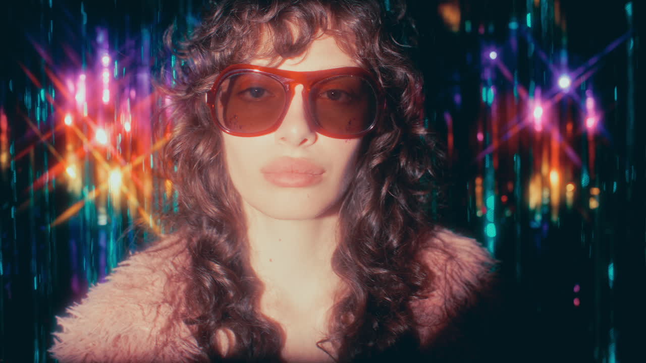 Portrait of Young Stylish Woman in Sunglasses against Fringe Curtain