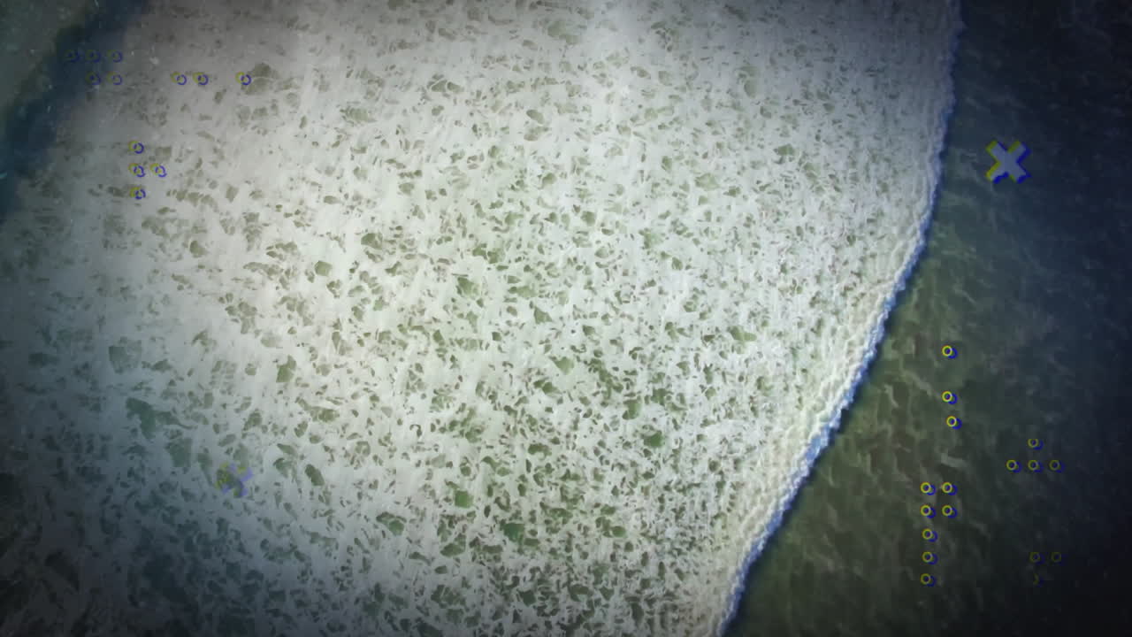 Ocean waves meeting sandy beach with colorful digital animation overlay